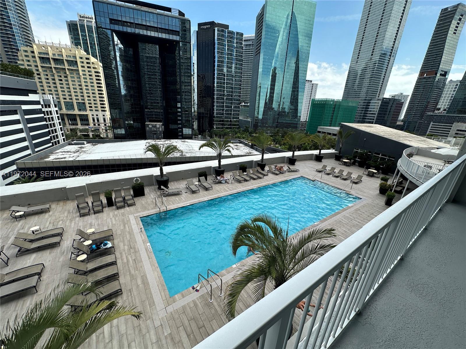 An elevated view of a rectangular swimming pool surrounded by lounge chairs and palm trees — 1250 S Miami Ave # 1012, Miami FL 33130, MIAMI, FL