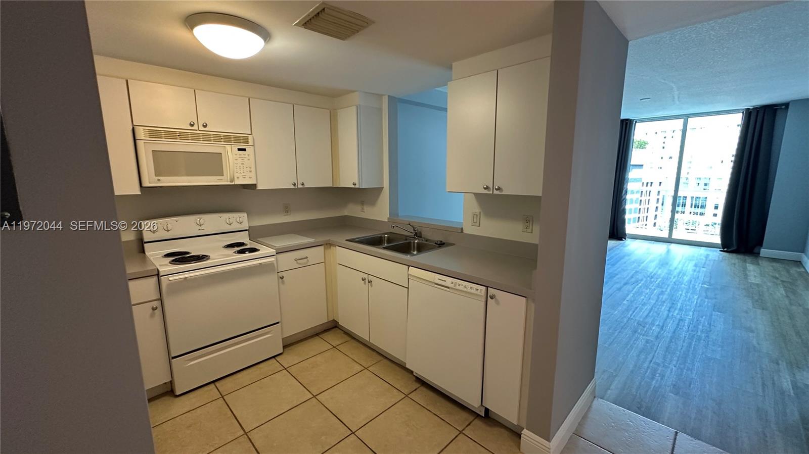 A kitchen with white cabinets, white appliances, and light-colored countertops features tiled flooring — 1250 S Miami Ave # 1012, Miami FL 33130, MIAMI, FL