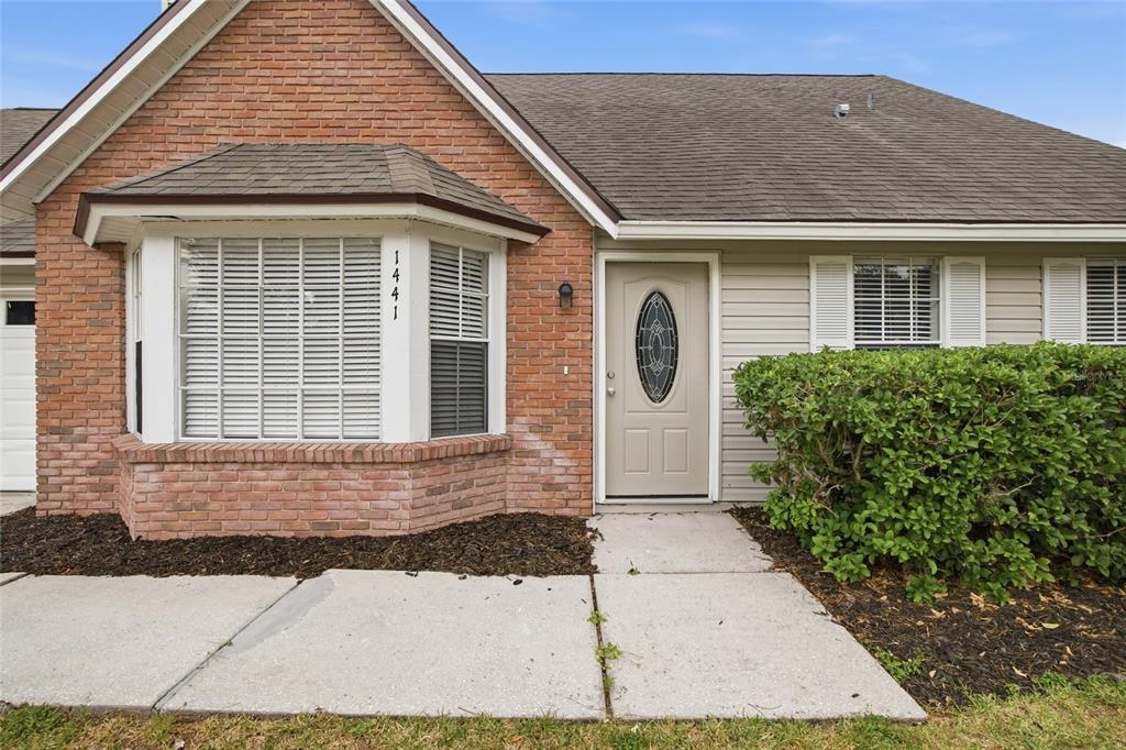 A brick and beige siding house exterior features a bay window and a front door — 1441 MONTE LAKE DRIVE, VALRICO, FL