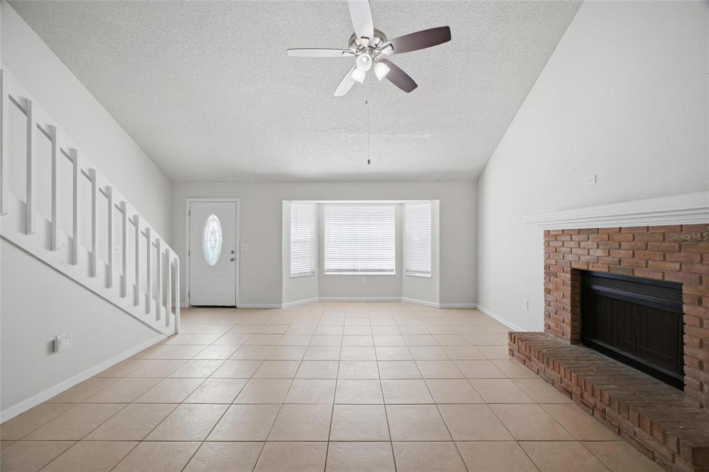 A living room with tile flooring, a brick fireplace, a ceiling fan, and a staircase — 1441 MONTE LAKE DRIVE, VALRICO, FL