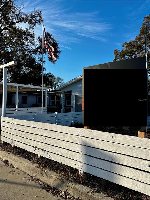 A white wooden fence stands in front of a building with an American flag — 5145 GULFPORT BOULEVARD S, GULFPORT, FL