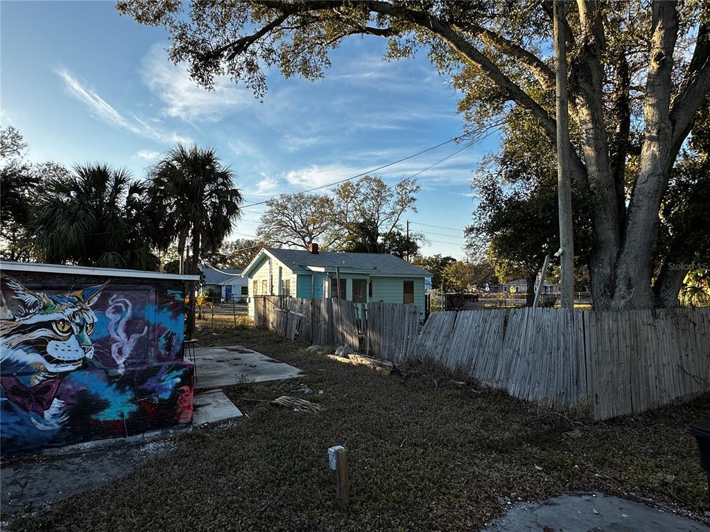 A light green house stands behind a weathered wooden fence next to a cat mural — 5145 GULFPORT BOULEVARD S, GULFPORT, FL