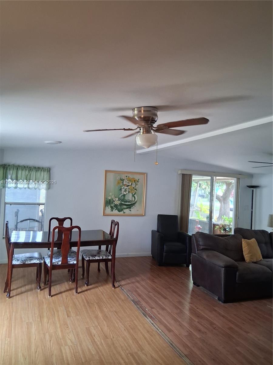 A dining area and living room feature wood-look flooring, a ceiling fan, and sliding doors — 5030 SW 30th Ave, Dania Beach FL 33312, DANIA BEACH, FL