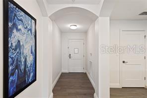 A hallway features white walls, dark wood flooring, an arched ceiling, and framed abstract art — 14501 GROVE RESORT AVENUE UNIT 2527, WINTER GARDEN, FL