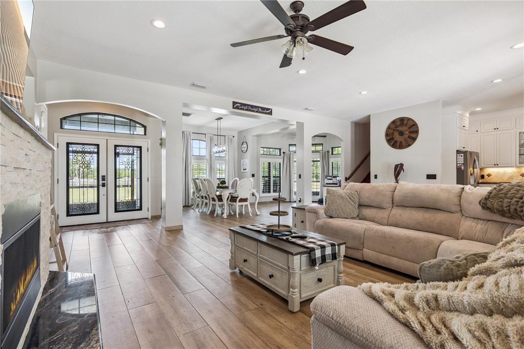 A living room with wood-look tile floors, a fireplace, and an open dining area — 345 CYPRESS ISLES ROAD, OSTEEN, FL