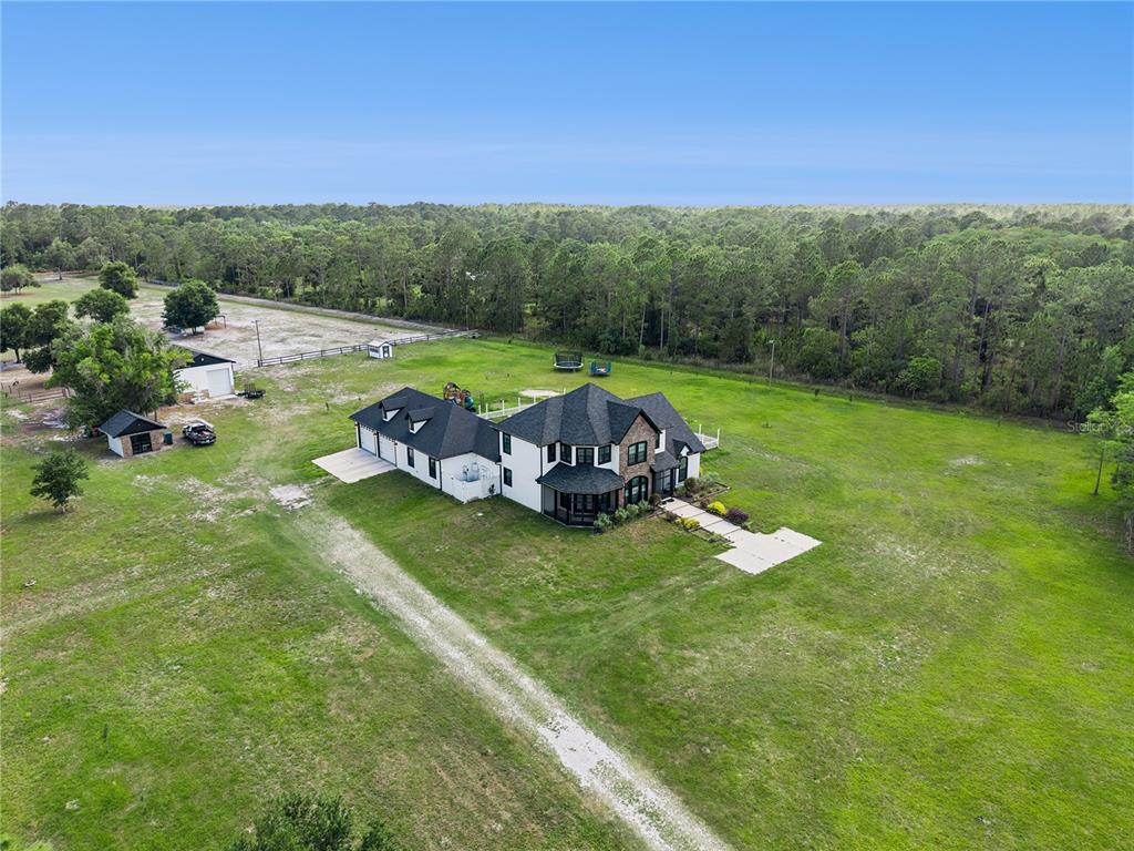 An aerial view shows a white house with a dark roof on a large lot — 345 CYPRESS ISLES ROAD, OSTEEN, FL