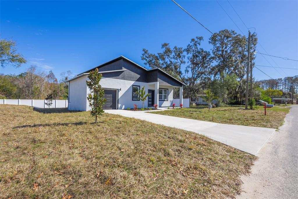 A modern, single-story house with a white exterior, dark roof, and a concrete driveway — 9912 GOLDEN LOOP, NEW PORT RICHEY, FL