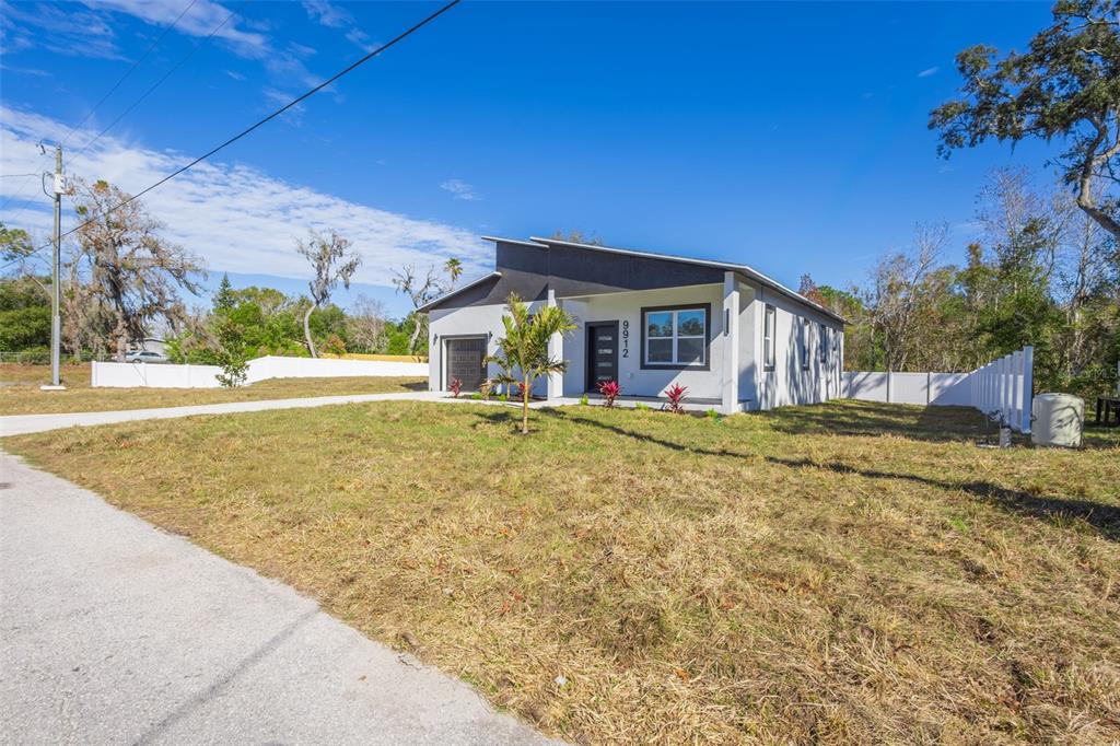 A modern, single-story house with a slanted roof stands on a grassy lot — 9912 GOLDEN LOOP, NEW PORT RICHEY, FL