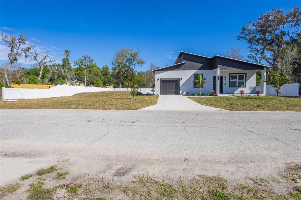 A modern single-story house with a white exterior, dark roof, and a concrete driveway — 9912 GOLDEN LOOP, NEW PORT RICHEY, FL