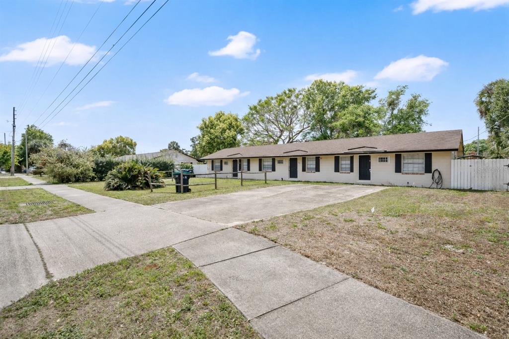 A single-story multi-unit building with a concrete driveway and a wooden fence in the yard — 722 TUCKER AVENUE, ORLANDO, FL