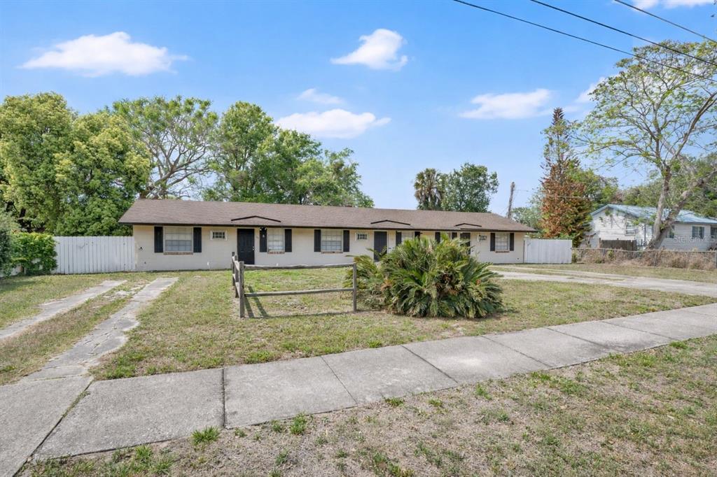 A single-story multi-unit building with a beige exterior, dark roof, and a front lawn — 722 TUCKER AVENUE, ORLANDO, FL