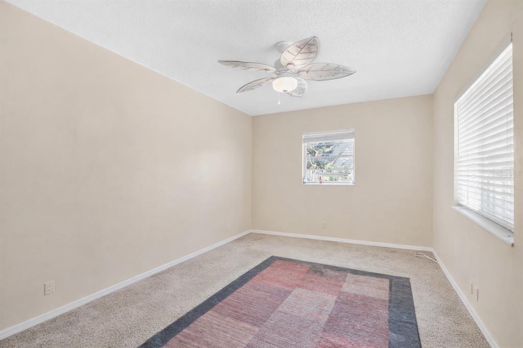 An empty bedroom with beige walls, beige carpeting, a ceiling fan, and two windows — 722 TUCKER AVENUE, ORLANDO, FL