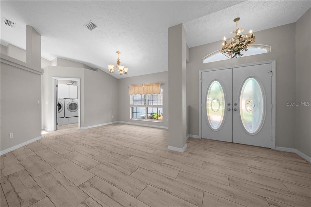 An entryway with light wood-look tile flooring, a double front door, and a chandelier — 10707 SW 74TH AVENUE, OCALA, FL
