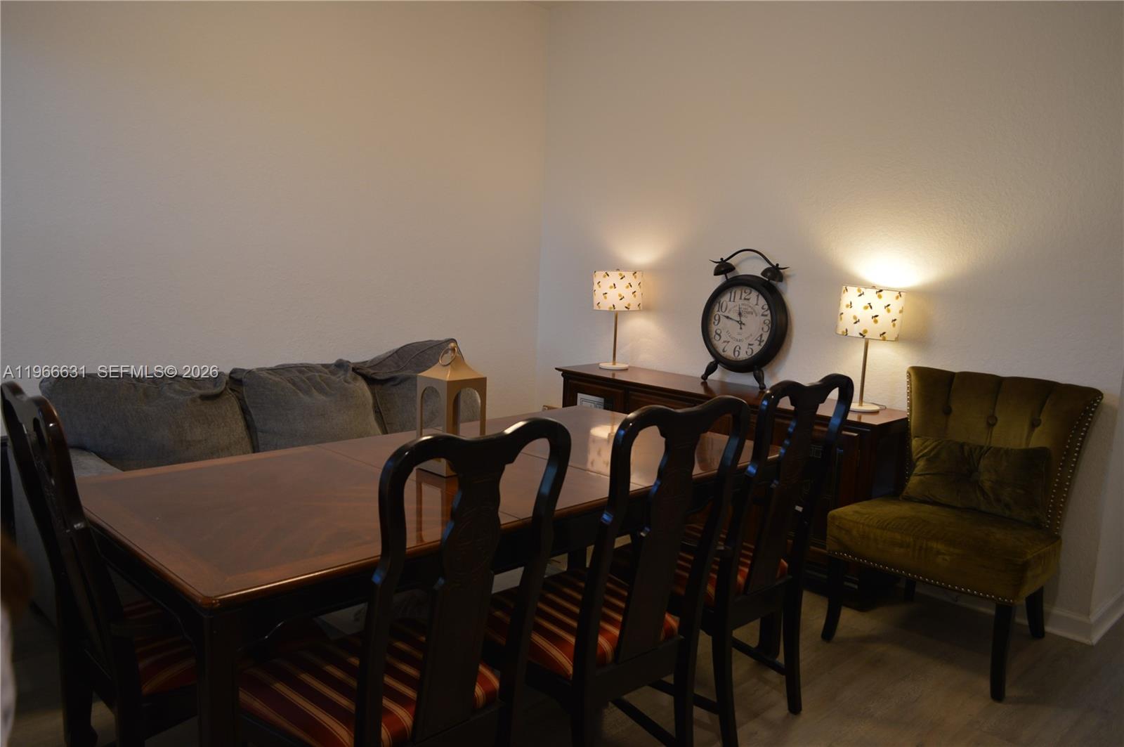 A dining room features a wooden table with striped chairs, a sideboard, and lamps — 1522 SE 26th Ter, Homestead FL 33035, HOMESTEAD, FL