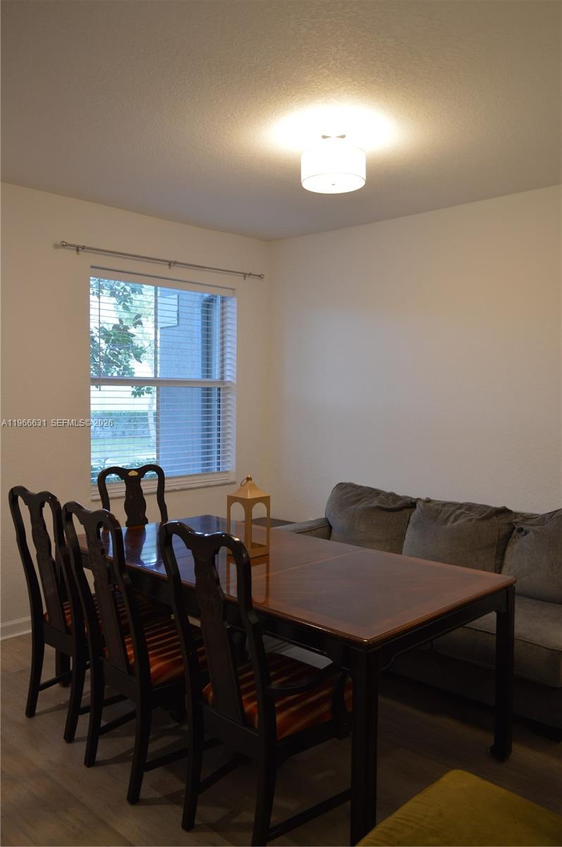 A dining area features a dark wood table with matching chairs and a gray sofa — 1522 SE 26th Ter, Homestead FL 33035, HOMESTEAD, FL