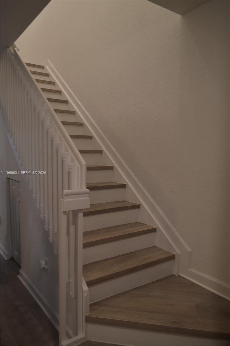A staircase with wood-look treads and white risers features a white railing and balusters — 1522 SE 26th Ter, Homestead FL 33035, HOMESTEAD, FL