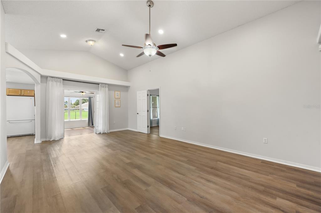 A spacious living room features vaulted ceilings, wood-look flooring, and an adjacent sunroom — 2965 COOL BREEZE CIRCLE, ST CLOUD, FL