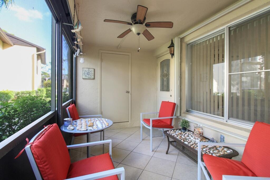 A screened-in patio features tile flooring, a ceiling fan, and four chairs with red cushions — 407 Pine Glen Lane # 1, FL 33463, FL