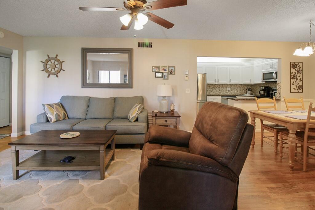 A living room with a gray sofa, brown recliner, coffee table, and adjacent dining area — 407 Pine Glen Lane # 1, FL 33463, FL