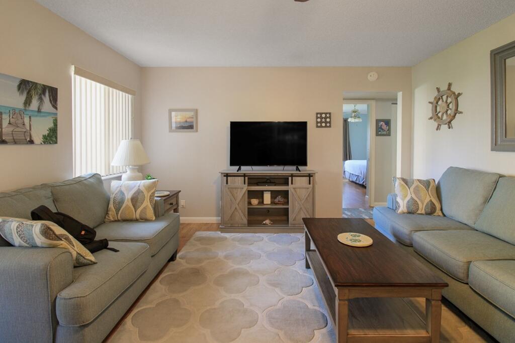 A living room features two light blue sofas, a wooden coffee table, and a television — 407 Pine Glen Lane # 1, FL 33463, FL