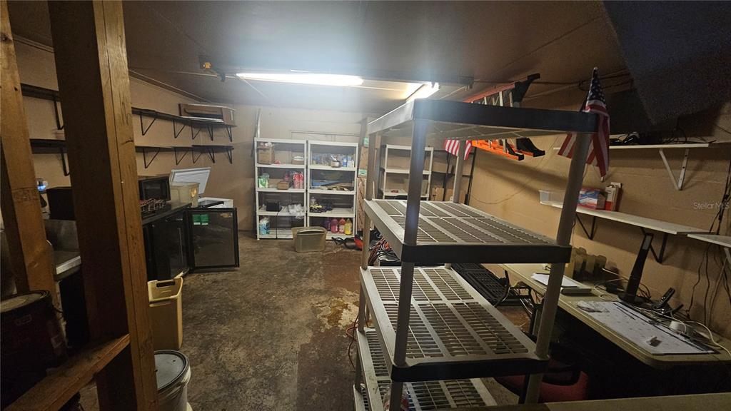 A cluttered garage features concrete floors, metal shelving units, and wall-mounted storage racks — 508 CYPRESS GARDENS BOULEVARD, WINTER HAVEN, FL