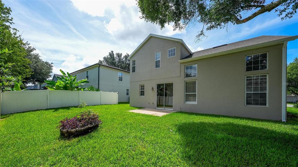 The exterior rear view of a two-story house features a lawn, patio, and white fence — 3626 OAK BROOK LANE, EUSTIS, FL