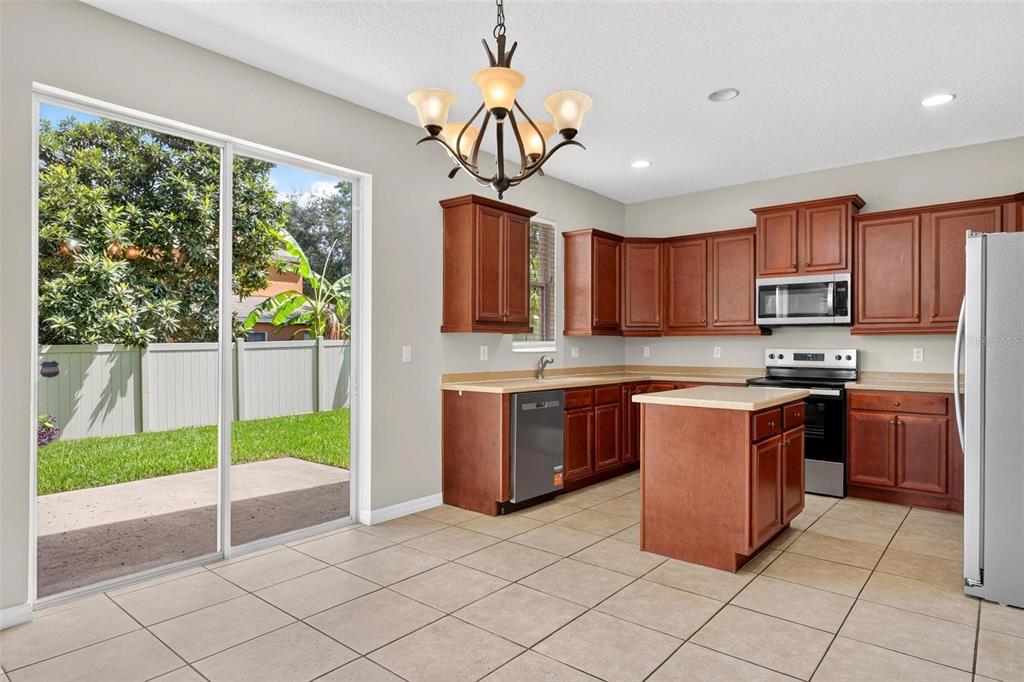A kitchen with wood cabinets, a center island, and a sliding glass door to the yard — 3626 OAK BROOK LANE, EUSTIS, FL