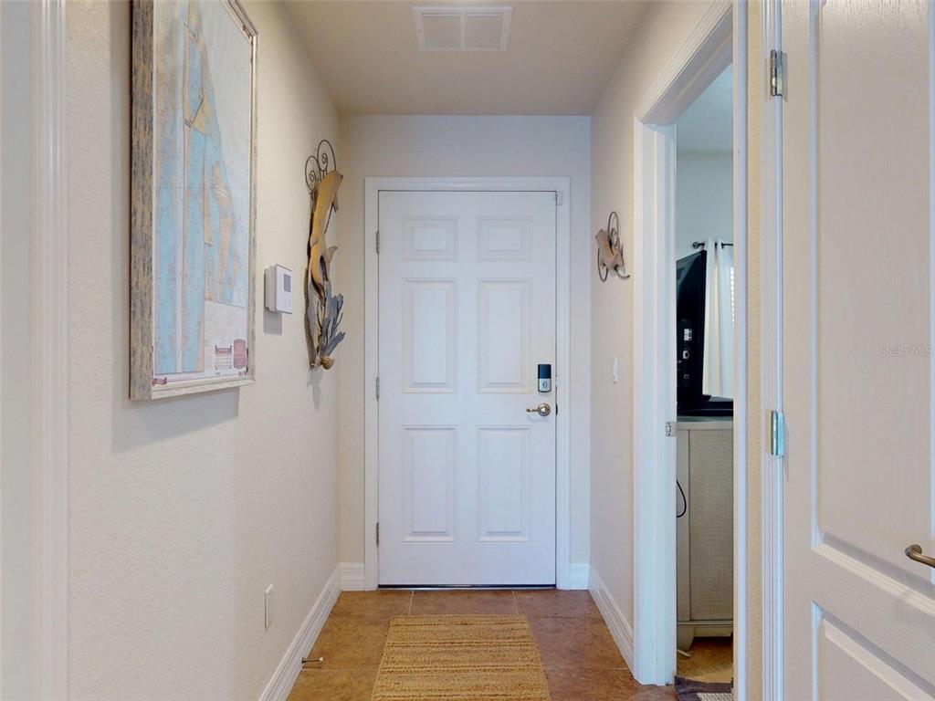A tiled entryway features a white front door, a framed map, and wall decor — 5300 S ATLANTIC AVENUE UNIT 505, NEW SMYRNA BEACH, FL
