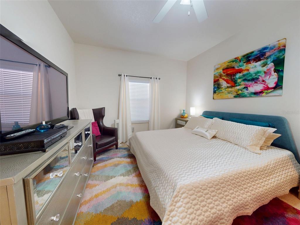 A bedroom features a bed with a blue headboard, a dresser, and a colorful rug — 5300 S ATLANTIC AVENUE UNIT 505, NEW SMYRNA BEACH, FL