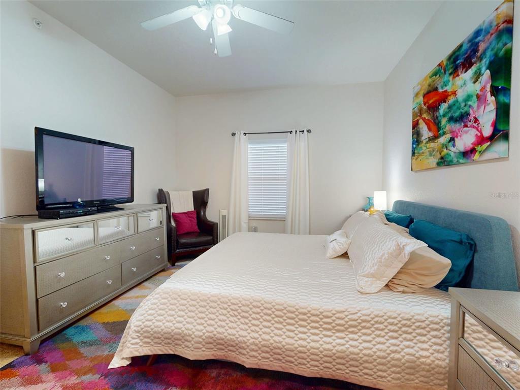 A bedroom features a bed with a blue headboard, a dresser, and a colorful rug — 5300 S ATLANTIC AVENUE UNIT 505, NEW SMYRNA BEACH, FL