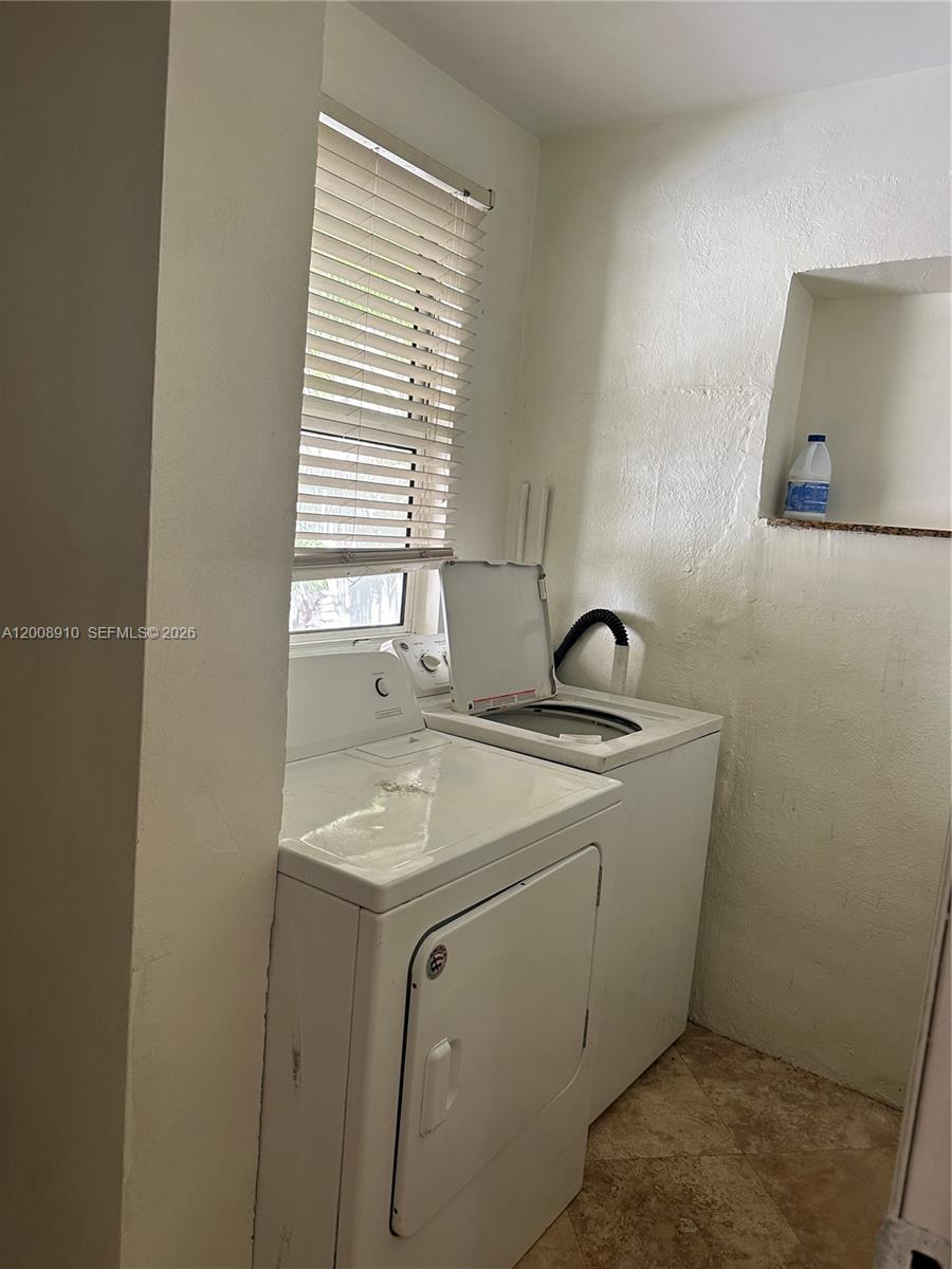 A laundry room features a white washer and dryer set beneath a window with blinds — 1422 Wiley St, Hollywood FL 33020, HOLLYWOOD, FL