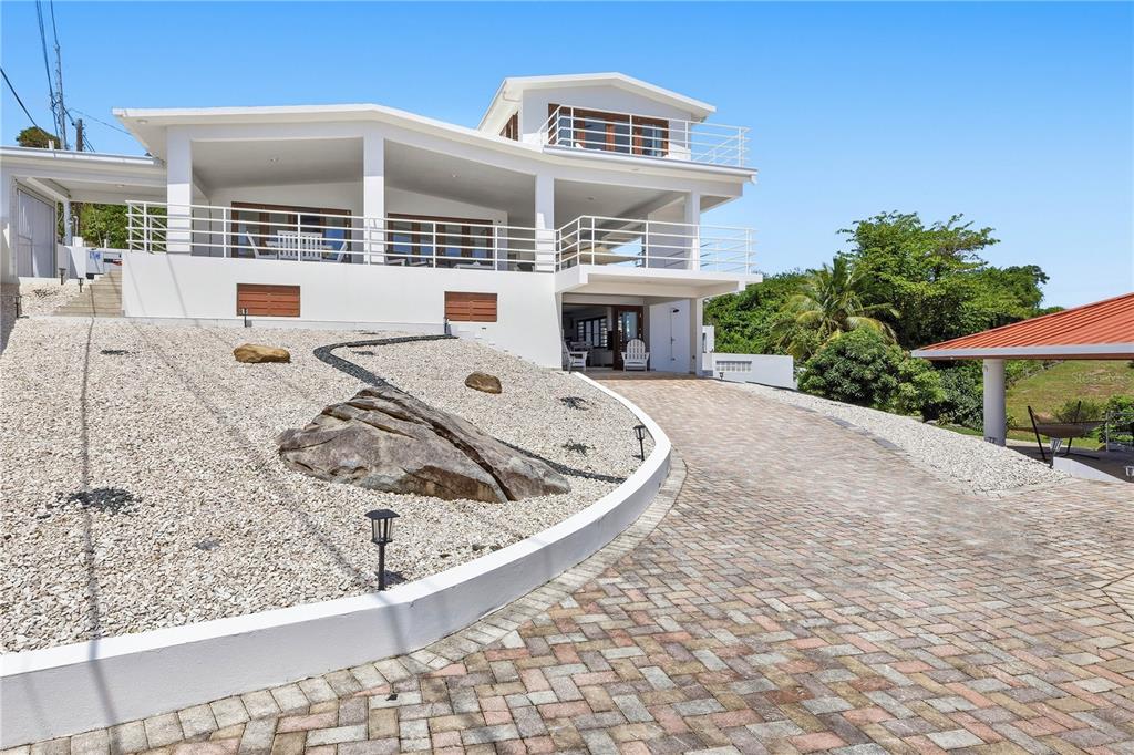 A multi-level white house with a paved driveway and a gravel yard with large rocks — 94 EL COCAL COUNTRY AND BEACH CLUB, YABUCOA, PR