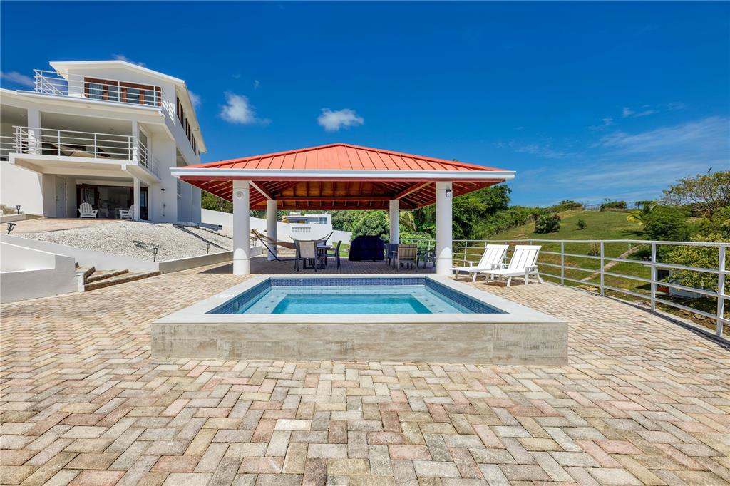 A rectangular pool sits on a paved patio beneath a red-roofed pavilion near a house — 94 EL COCAL COUNTRY AND BEACH CLUB, YABUCOA, PR