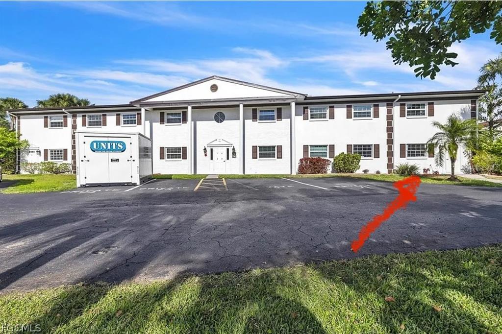 A two-story white building with brown shutters and a portable storage unit in front — 7043 NEW POST DR UNIT 4, NORTH FORT MYERS, FL