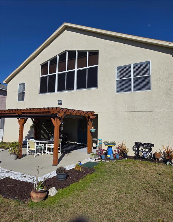 The exterior of a two-story house features a wooden pergola over a concrete patio — 6719 MANOR BEACH, NEW PORT RICHEY, FL