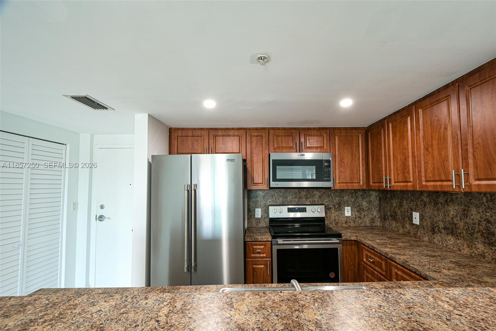 A kitchen features wood cabinets, stainless steel appliances, and brown granite countertops — 2740 SW 28th Ter # 603, Miami FL 33133, MIAMI, FL