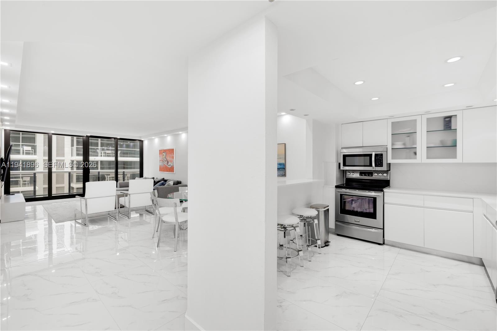 A bright, open-concept kitchen and living area features white cabinetry, marble-look tile floors, and balcony access — 9455 Collins Ave # 806, Surfside FL 33154, SURFSIDE, FL