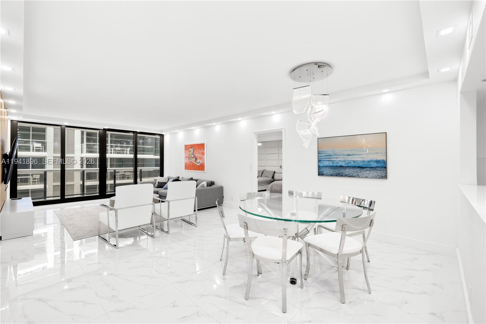 A bright, open-concept living and dining area features white marble floors and modern furniture — 9455 Collins Ave # 806, Surfside FL 33154, SURFSIDE, FL