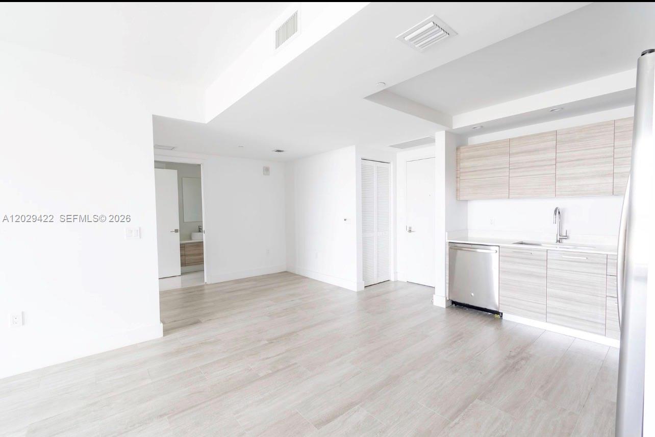 A bright, modern kitchen and living area features light wood-look flooring and cabinetry — 121 NE 34th St # 1412, Miami FL 33137, MIAMI, FL