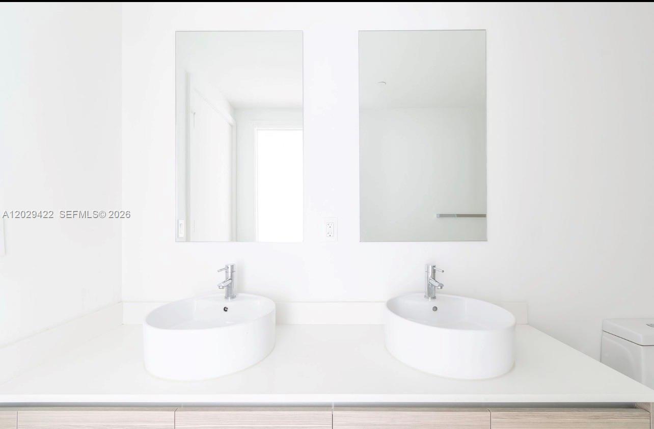 A modern bathroom features a white double vanity with vessel sinks and two rectangular mirrors — 121 NE 34th St # 1412, Miami FL 33137, MIAMI, FL