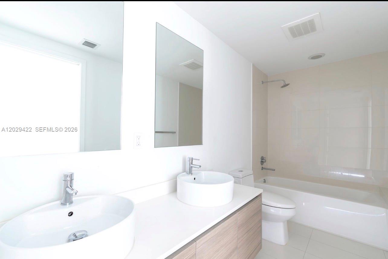 A modern bathroom features a double vanity with vessel sinks and a tiled shower-tub combination — 121 NE 34th St # 1412, Miami FL 33137, MIAMI, FL