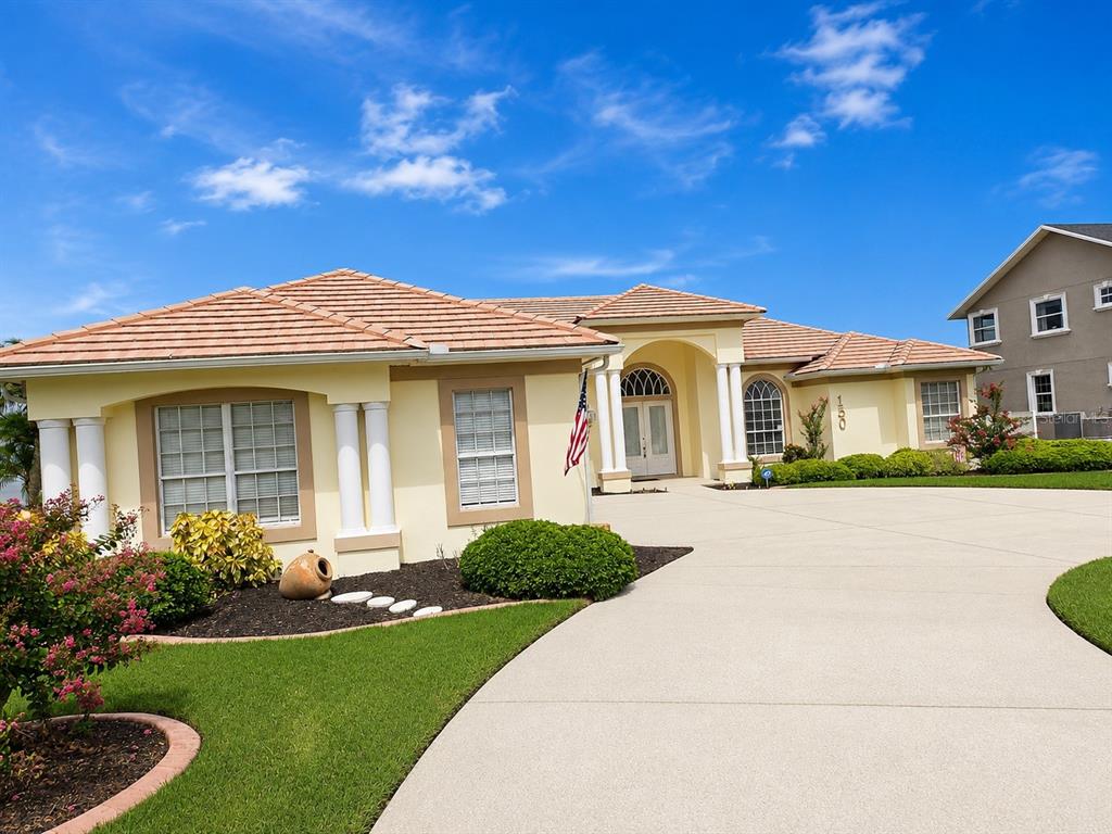 A single-story house with a light yellow exterior, tiled roof, and a large concrete driveway — 150 OLD NICHOLS CIRCLE, AUBURNDALE, FL
