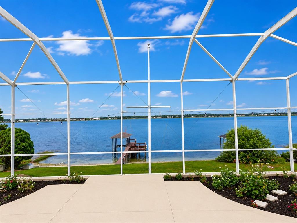 A view of a lake and dock from a screened-in patio with concrete flooring — 150 OLD NICHOLS CIRCLE, AUBURNDALE, FL