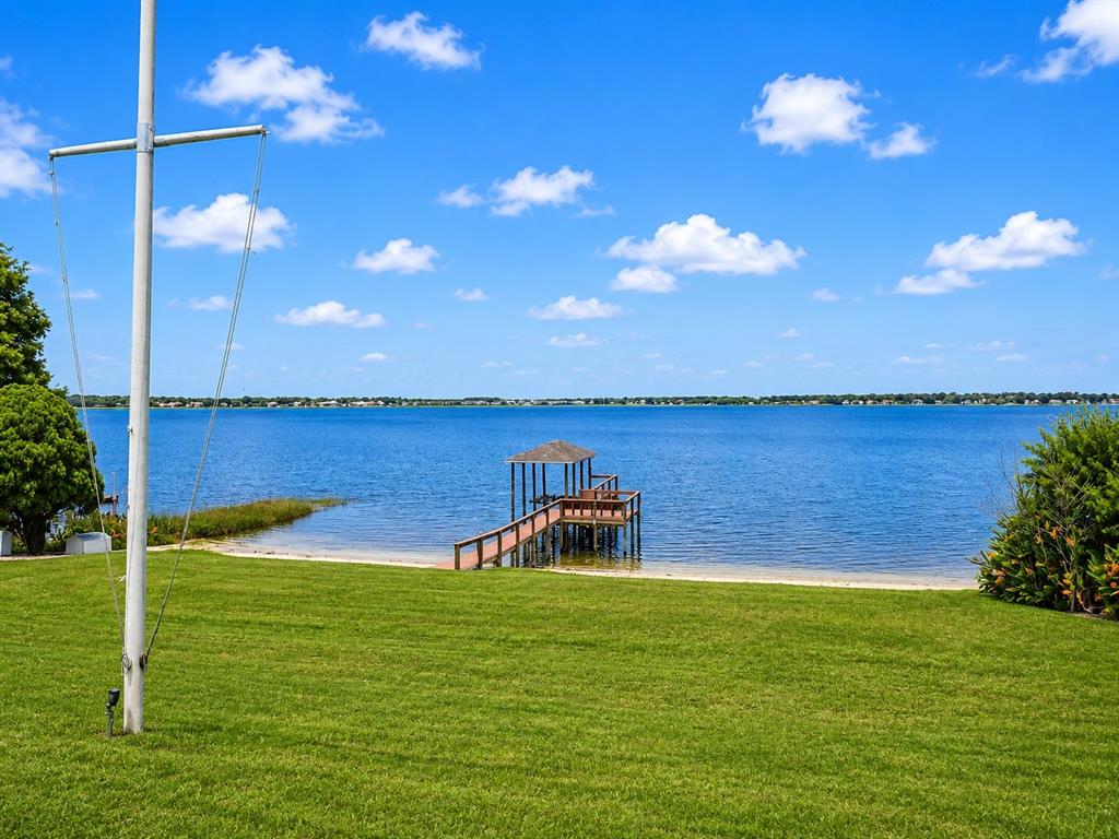 A grassy lawn leads to a wooden dock on a lake under a blue sky — 150 OLD NICHOLS CIRCLE, AUBURNDALE, FL