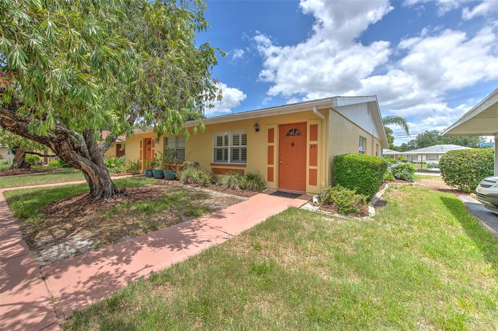 A single-story yellow house with an orange front door and a concrete walkway — 401 DORCHESTER PLACE UNIT 49, SUN CITY CENTER, FL