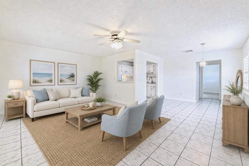 A bright living room features white walls, tile flooring, a beige sofa, and two armchairs — 401 DORCHESTER PLACE UNIT 49, SUN CITY CENTER, FL