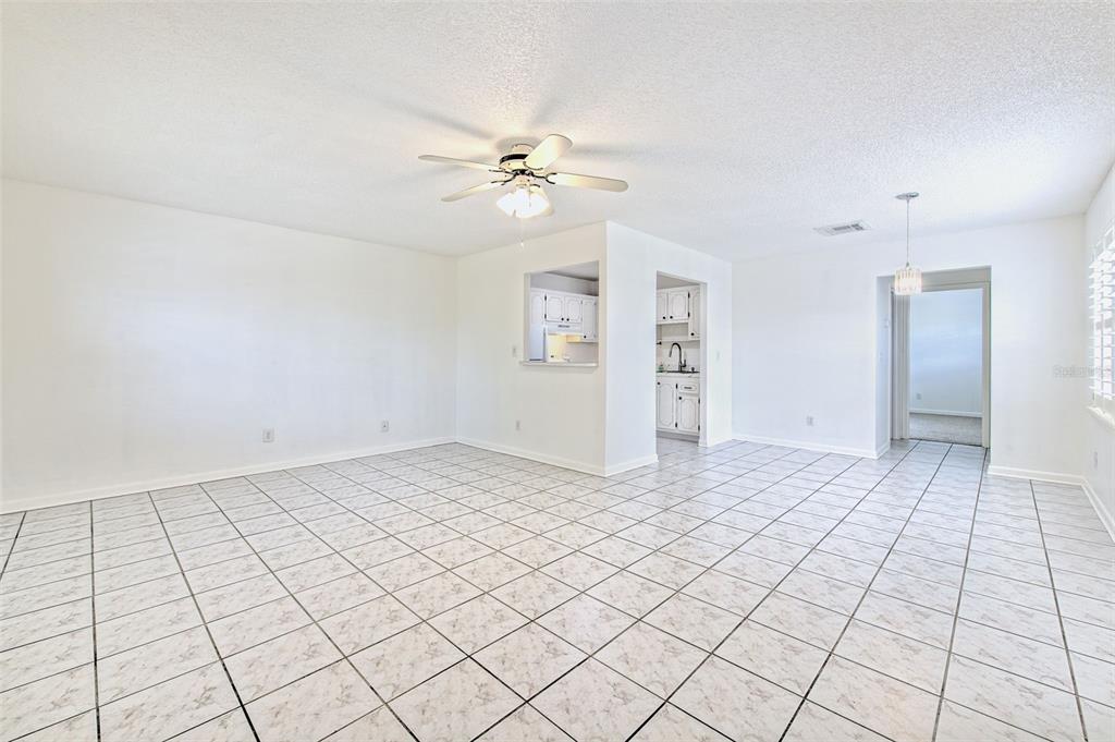 A bright, open-concept living area features white walls, a ceiling fan, and tiled flooring — 401 DORCHESTER PLACE UNIT 49, SUN CITY CENTER, FL
