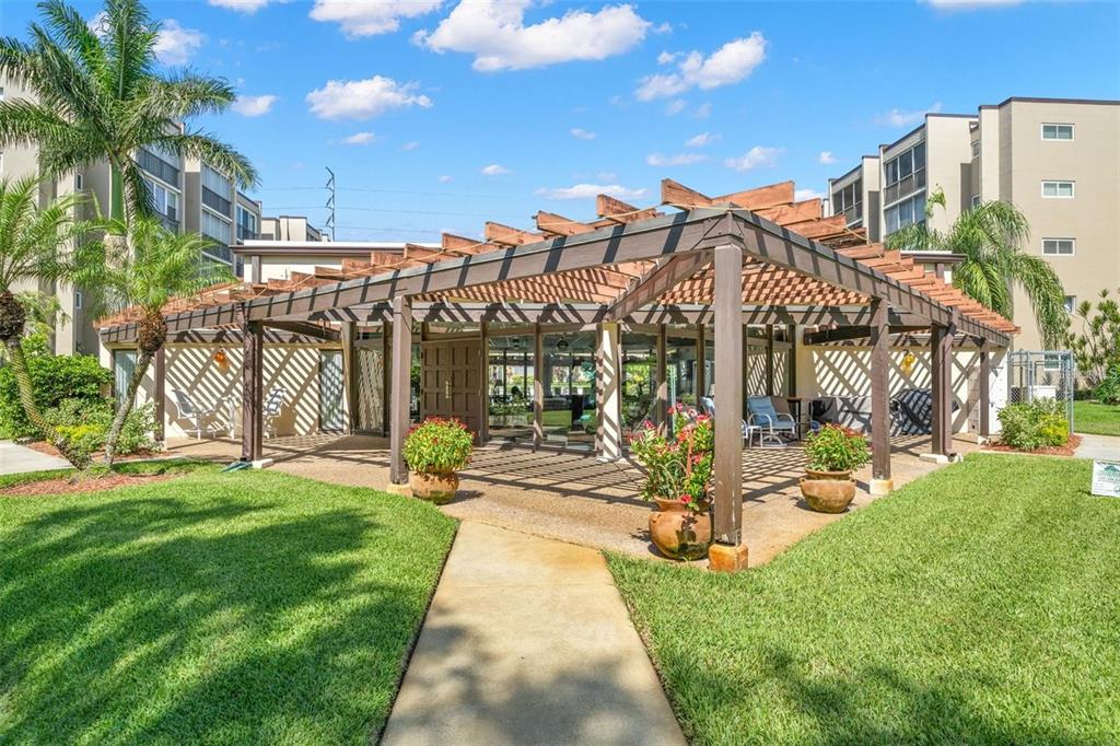 A concrete walkway leads to a wooden pergola covering a patio area with potted plants — 1247 S MARTIN LUTHER KING JR AVENUE UNIT D103, CLEARWATER, FL