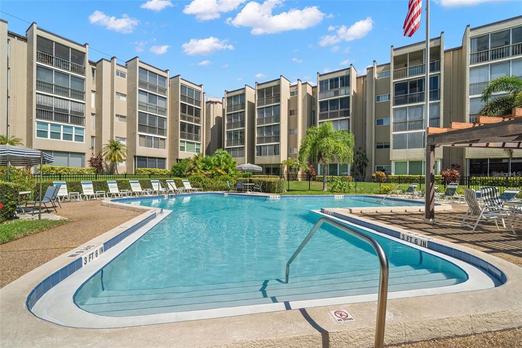 A swimming pool with lounge chairs sits in front of a multi-story apartment complex — 1247 S MARTIN LUTHER KING JR AVENUE UNIT D103, CLEARWATER, FL
