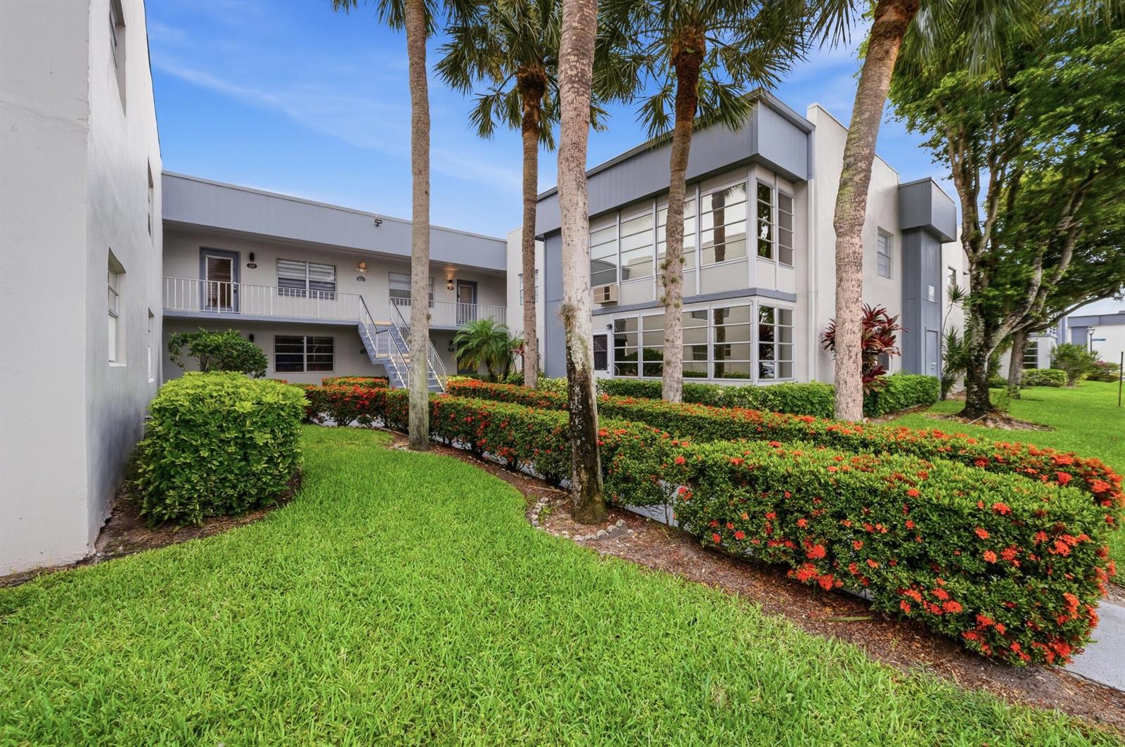 A two-story apartment building features gray exterior walls, palm trees, and a landscaped hedge — 330 Piedmont # 330, Delray Beach FL 33484, DELRAY BEACH, FL